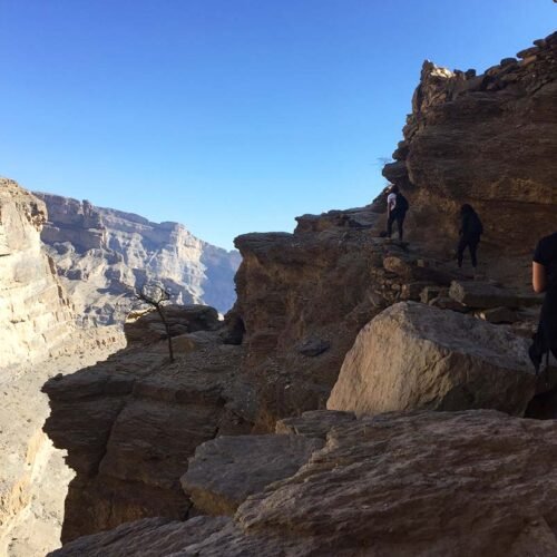 A walker on the rocky rim of the canyon on Jabal Shams