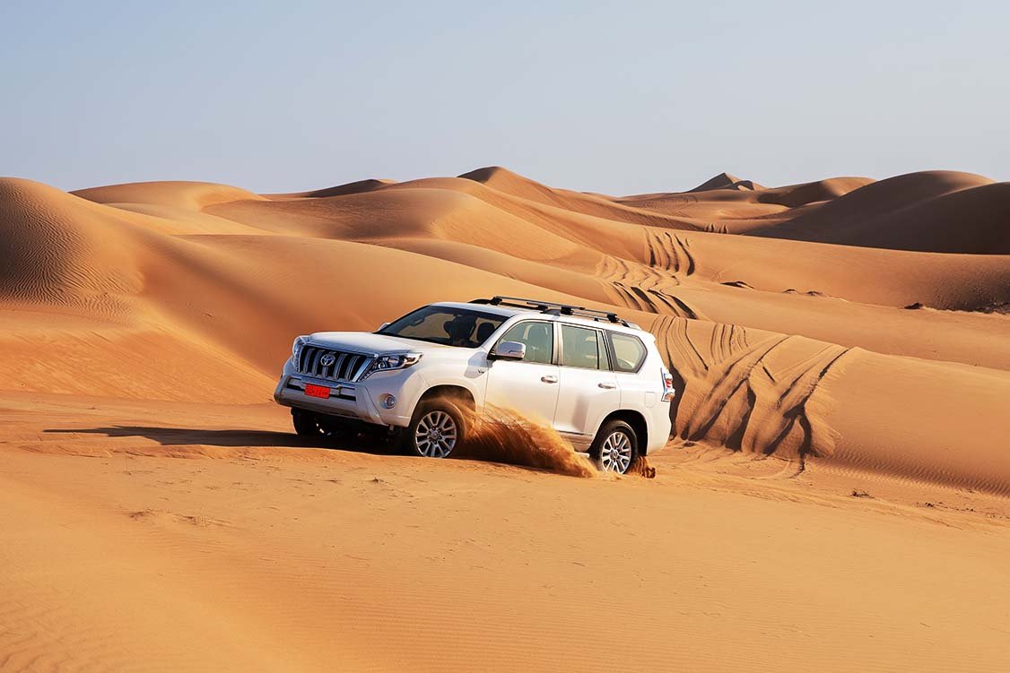 A four-wheel drive climbing a sand dune