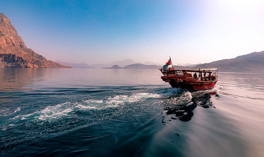 A dhow speeding through a fjord in Musandam