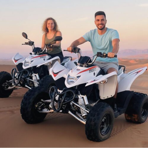 Two riders on quad bikes in the dunes