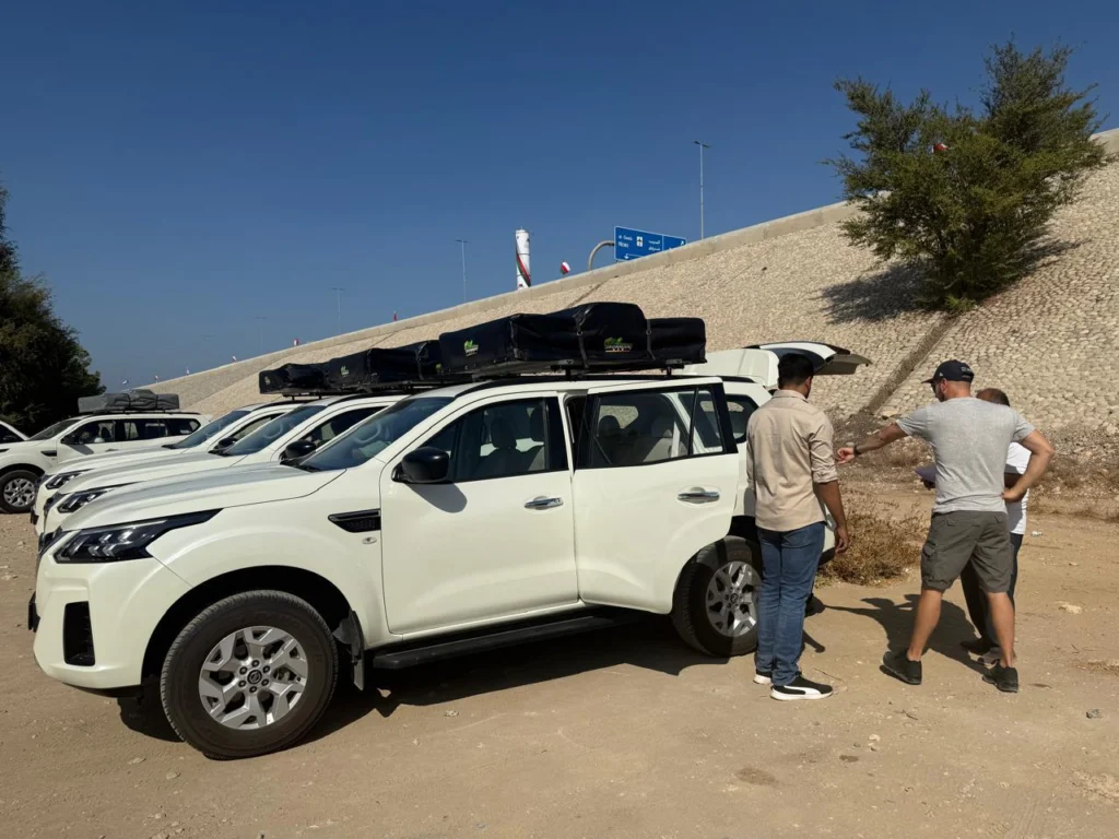 Two people beside a white 4x4 at a handover briefing, with more fleet vehicles behind