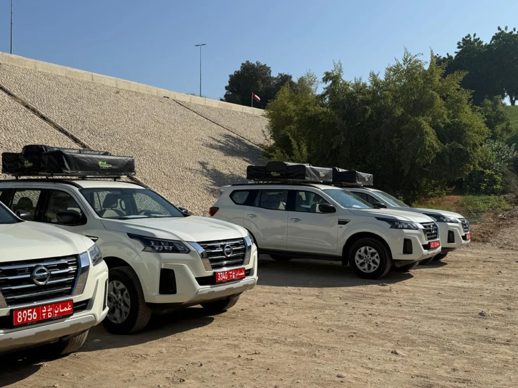 Three of our white 4x4s with roof racks lined up on a dirt lot before handover