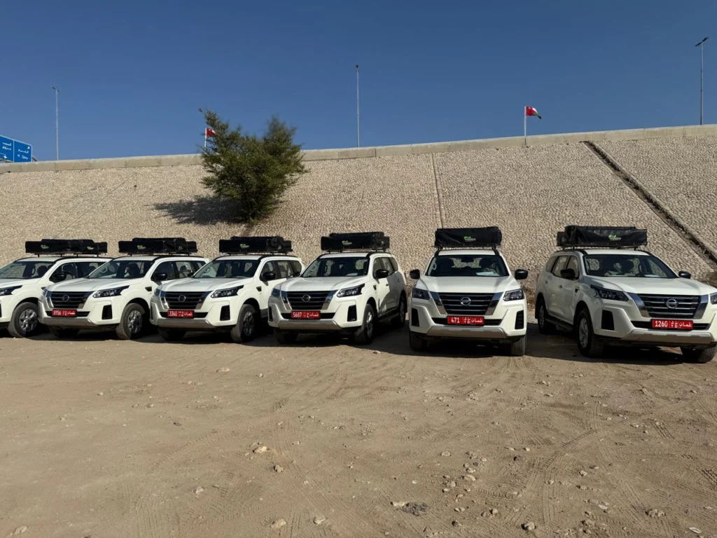 A long line of white fleet 4x4s parked in front of a sloping bank