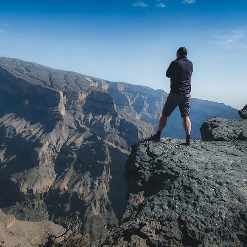 A hiker standing on the rim of the canyon on Jabal Shams
