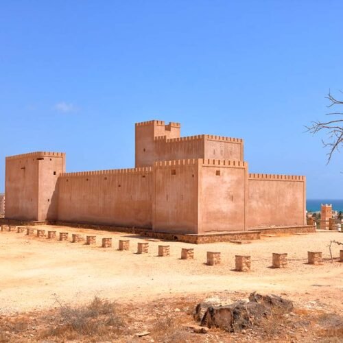 Taqah Castle, a sand-coloured fort under a blue sky