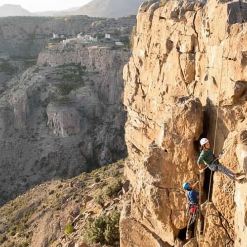 Climbers on a via ferrata on a cliff face above a canyon