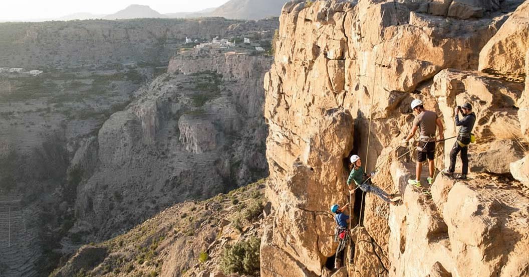 Climbers on a via ferrata on a cliff face above a canyon