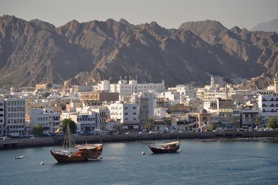Muscat waterfront with dhows in the harbour and mountains behind