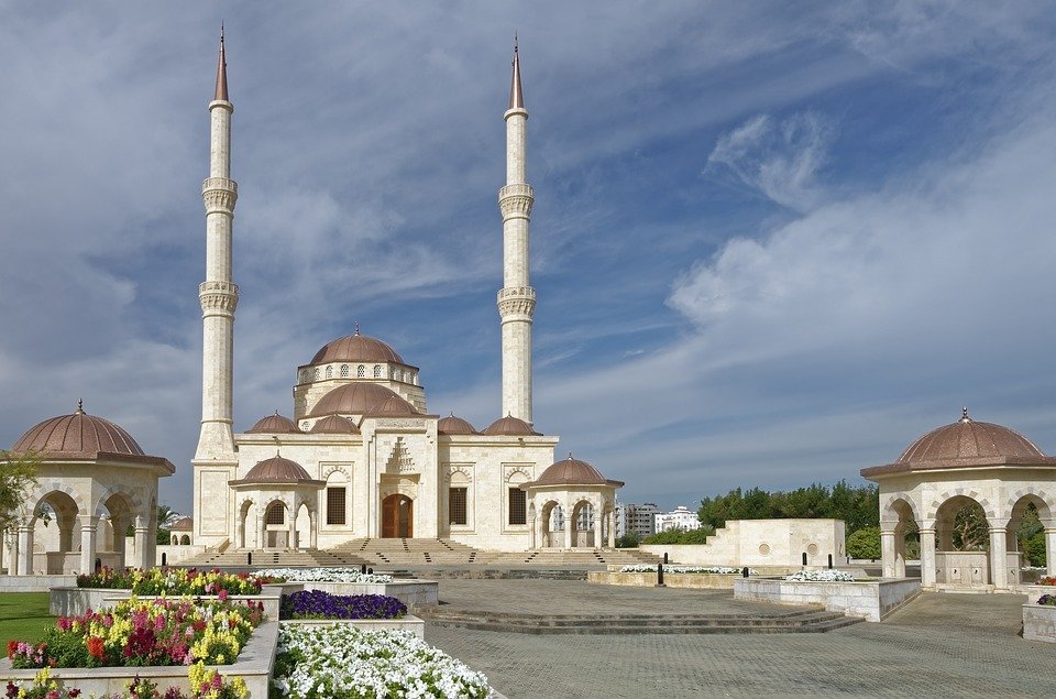White mosque with two minarets and domed pavilions