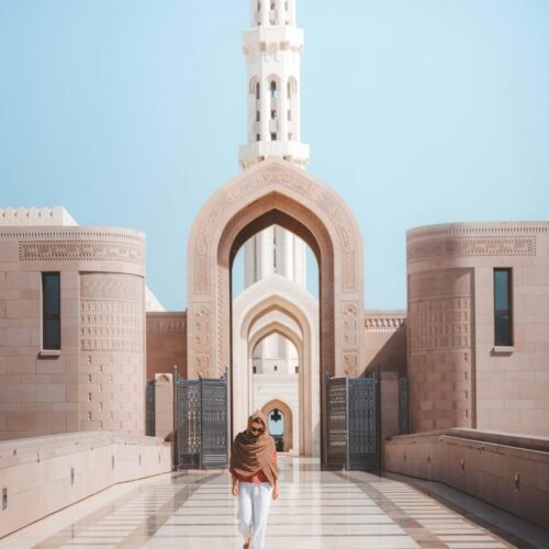 A man walking through an arched gateway at the Sultan Qaboos Grand Mosque