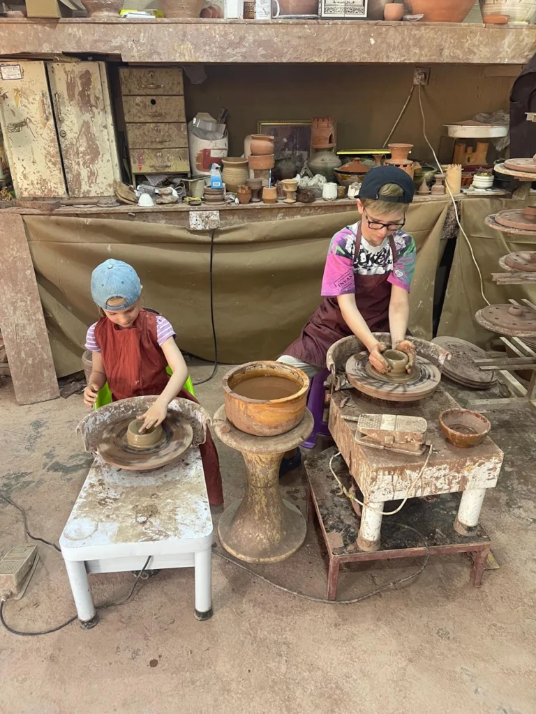 Two children making pottery on wheels in a traditional workshop