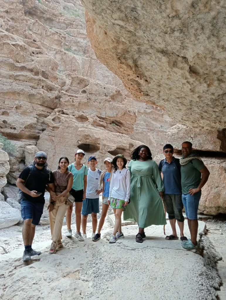 A group of guests and their guide standing under a rocky canyon overhang