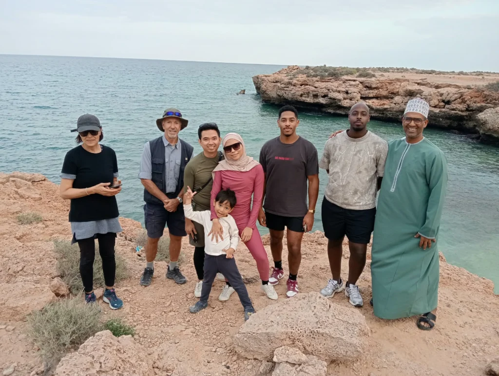 A family and guide posing on rocky coastal cliffs above the sea