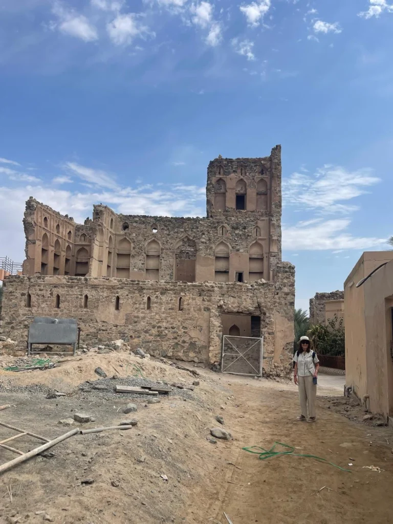 A guest standing in front of a ruined historic house