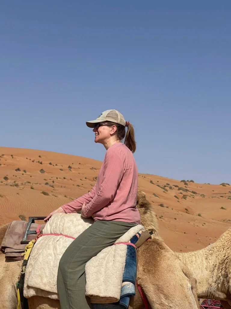 A guest riding a camel through the red sand dunes