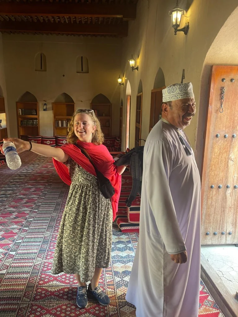 A guest laughing with an Omani guide inside a historic fort hall