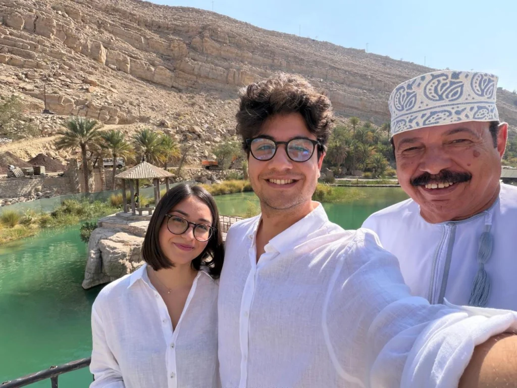 Two guests and their guide taking a selfie beside a green oasis pool