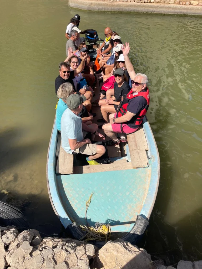 A boat full of waving guests crossing a water channel