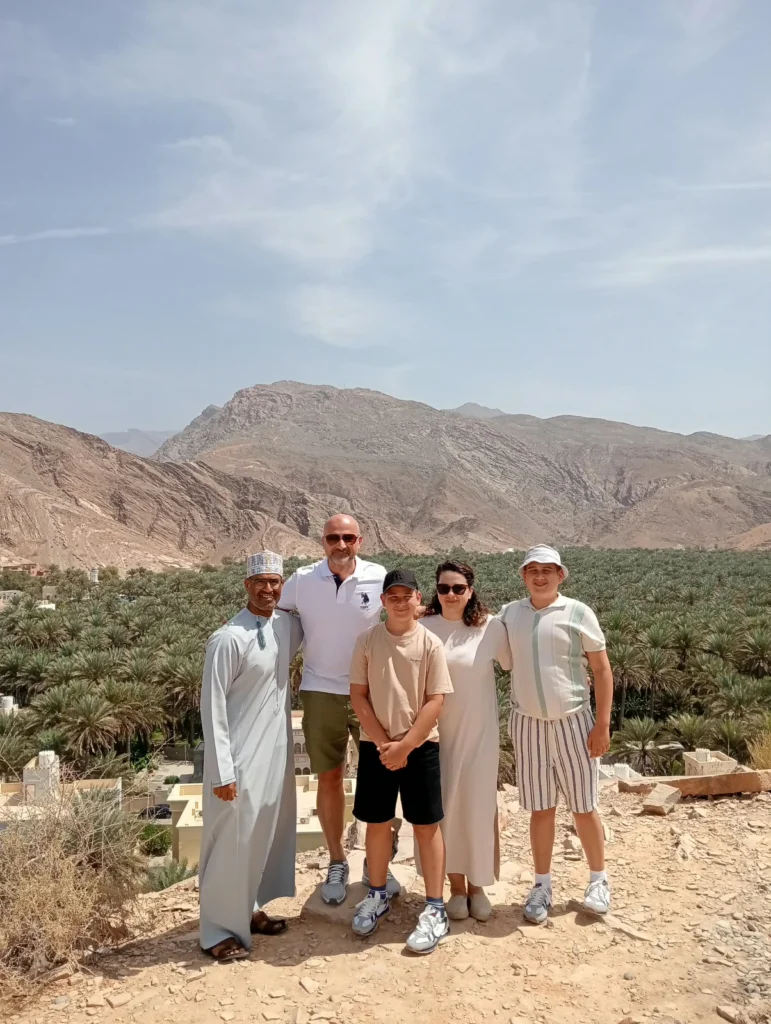 Guests and their guide on a hilltop above a date palm oasis