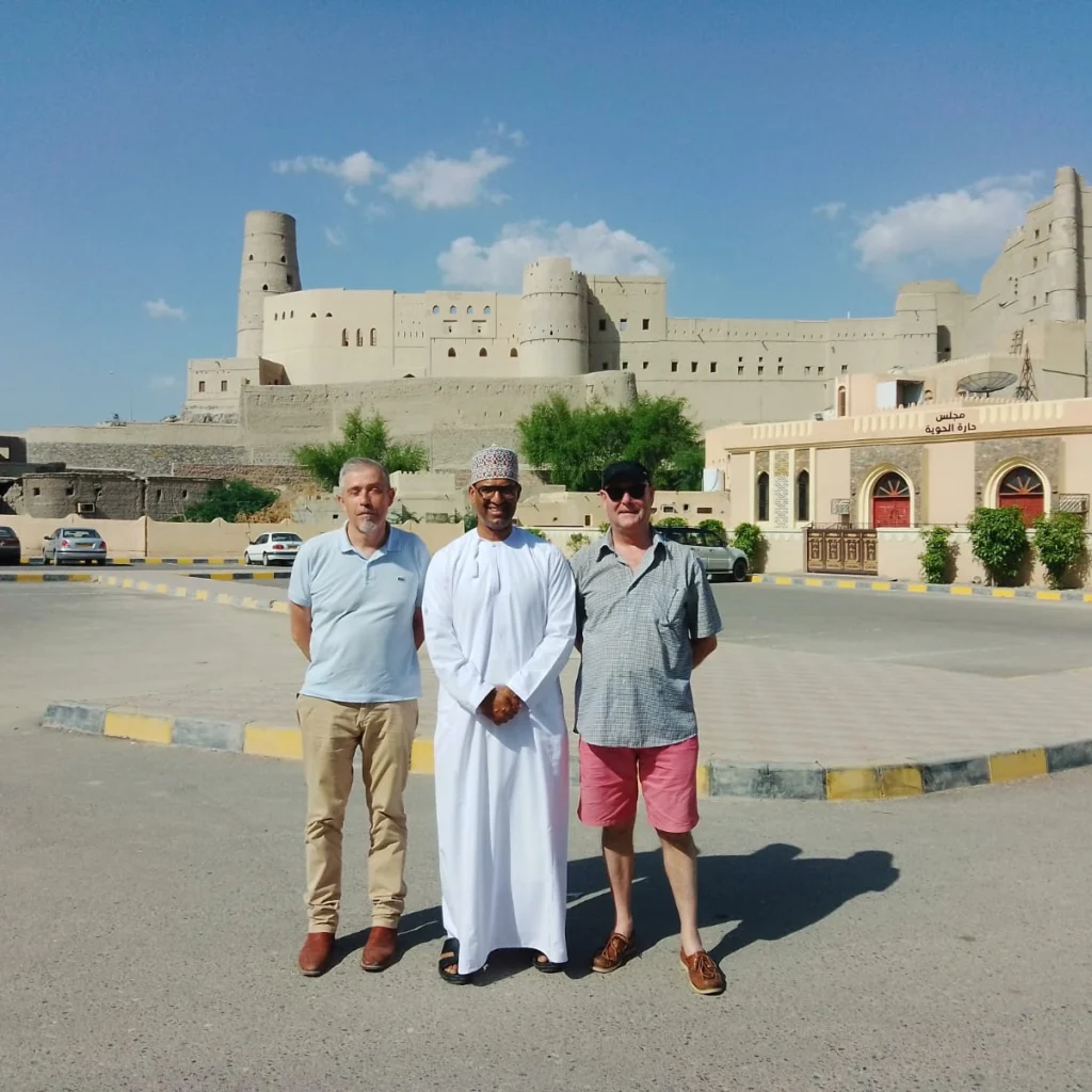 Two guests with an Omani guide in front of a historic fort