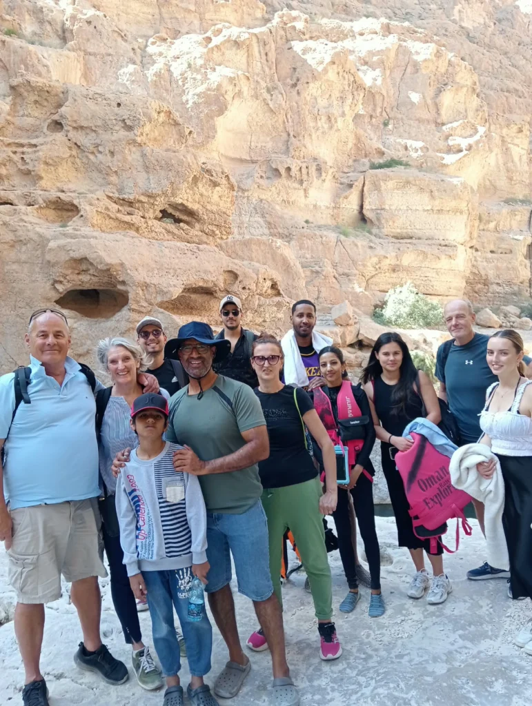 A large group of guests posing together in a rocky wadi canyon